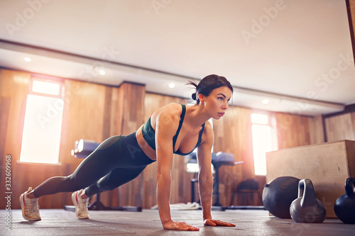 Fotografía young motivated girl doing plank exercise at gym, full length photo, copy space