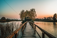 Landscape With A Wooden Bridge To The Fisherman's House On The River Island At Sunset