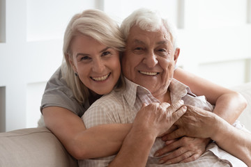 Wall Mural - head shot portrait smiling older wife and husband hugging, looking at camera, family posing for phot