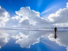 Surfer On Beach With Beautiful Clouds Reflections