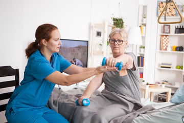 Female doctor helping elderly age woman with physiotherapy