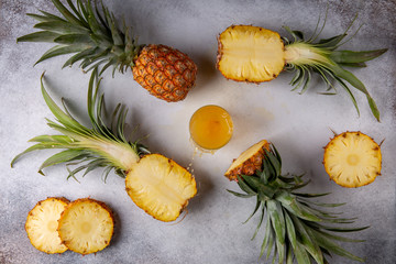 Wall Mural - Whole and sliced pineapple and glass of pineapple juice on gray background. Top view.