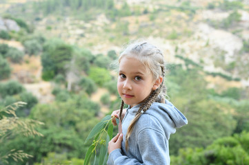 portrait of a cute little six year old European girl with pigtails, traveling with her family in the mountains of the island of Crete on summer vacations