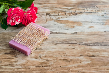 Handmade soap with a pink aroma , a bouquet of rose flowers on an old wooden table, retro style, rustic. Copy of space , empty space for text