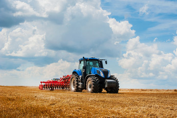 blue tractor in the field, agricultural machinery work, field and beautiful sky