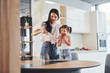© standret - Mother pouring fresh milk into the glass for her little daughter in kitchen