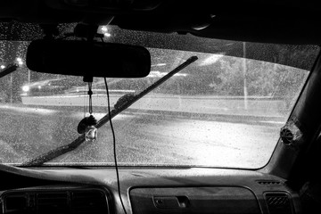 Wall Mural - beautiful drops of water on the windshield of the car with the glass cleaners turned on, during a thunderstorm and rain in the night city. front and back background blurred