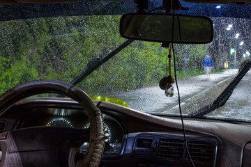 Wall Mural - beautiful drops of water on the windshield of the car with the glass cleaners turned on, during a thunderstorm and rain in the night city. front and back background blurred