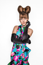 Pretty Young Girl Beauty Portrait. Elegant Fashion Glamorous Teen Model Wearing Black Glamour Gloves And Floral Dress. Bow Hairstyle And Make-up. Spring Fashion Concept.