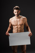 © LIGHTFIELD STUDIOS - happy sexy naked man holding blank placard isolated on black