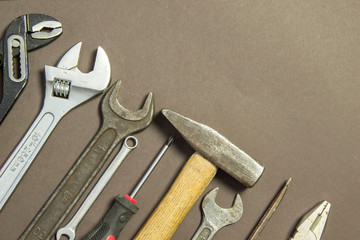 Construction tools on textured paper consisting of pipe wrench, screwdriver, metal, hammer and copy space for your text or product.