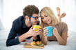 © DG PhotoStock - Lovely caucasian young couple enjoying breakfast set on the bed in bedroom together. Romantic caucasian couple's portrait in relaxation posing.