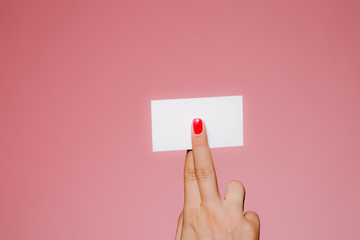 Woman's hand hold blank business card isolated on pink