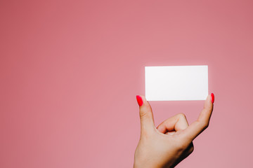 Woman's hand hold blank business card isolated on pink