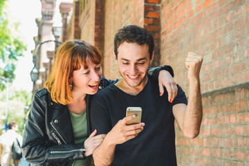 Young couple using mobile phone outdoors.