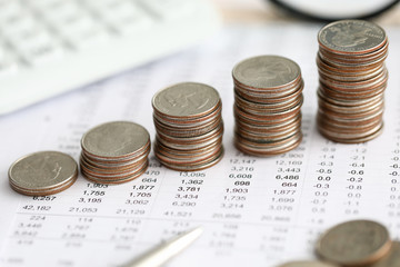 Row of silver coins standing at financial report paper