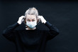 une jeune femme blonde se place un masque de protection sur le visage