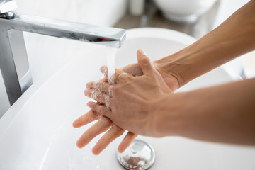 Close up female hands under running water in bathroom. After toilet woman wash her arms using antibacterial soap. Stop corona virus or 2019-ncov, good life habit, handwashing, personal hygiene concept