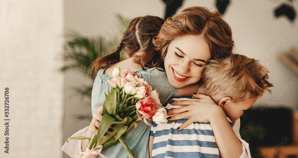 Little children congratulating and hug mother in kitchen. - obrazy, fototapety, plakaty 