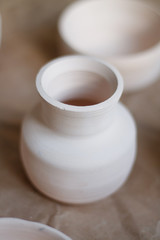 dishes made of white clay without glaze after firing on a brown background close-up. pottery