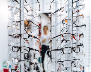 Wall Mural - Optometrist, optician or eye doctor showing glasses on blurred background. Many eyeglasses in shop.