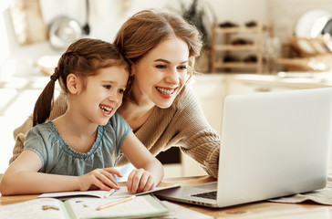 Wall Mural - Happy girl with mother studying online at home.