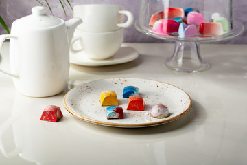 Wall Mural - Modern chocolate candy on white plate and white teapot on white table