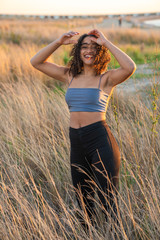 Wall Mural - curly black hair african american young woman posing smiling in field, vertical picture