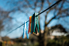 Six Clothespins Hanging On A Line With A Blurry Tree In The Background
