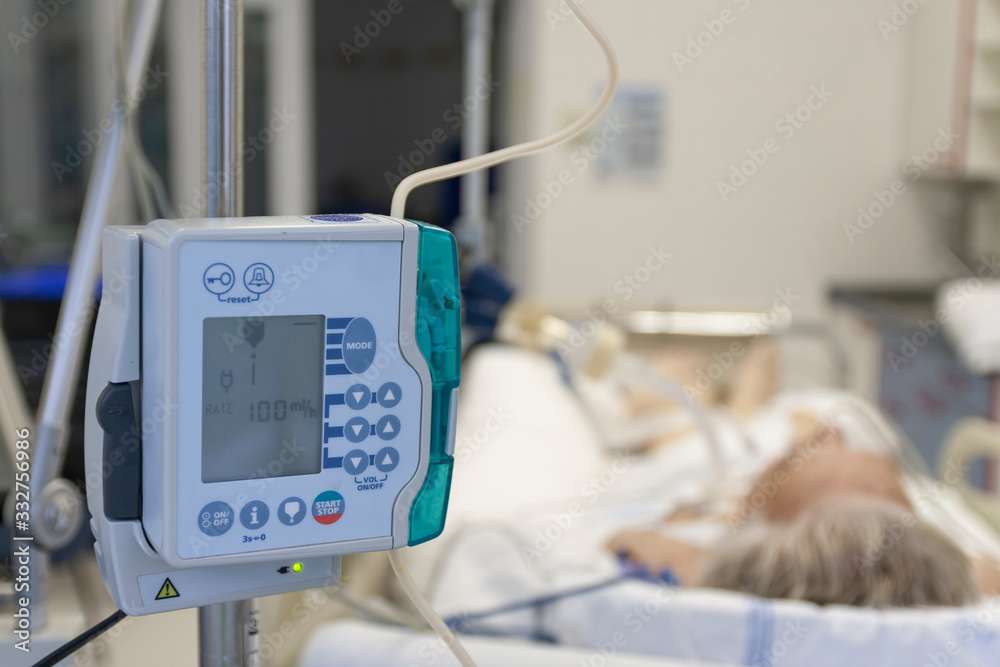 A small, lightweight, portable enteral feeding pump in ICU in hospital, on background patient in bed connected to medical ventilator in ICU in hospital - obrazy, fototapety, plakaty 