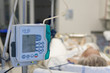 A small, lightweight, portable enteral feeding pump in ICU in hospital, on background patient in bed connected to medical ventilator in ICU in hospital