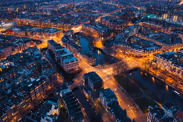 Wall Mural - Amsterdam Netherlands aerial view at night. Old dancing houses, river Amstel, canals with bridges, old european city landscape from above.