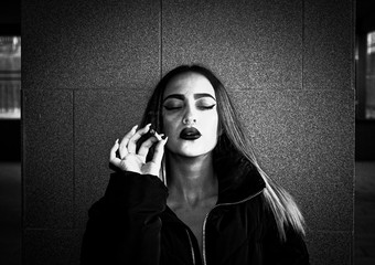 Blonde girl with red painted lips and nose piercing smoking a weed cigarette. Hipster style. Black and white.