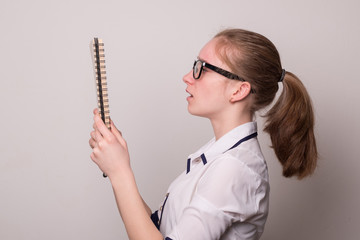Wall Mural - Cute girl in glasses with a notebook. Young girl holds a notebook and pen. Teenager is giving a school report.