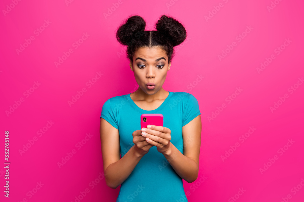 Photo of pretty shocked millennial dark skin lady hold telephone hands read blog comments open mouth bad news wear blue casual t-shirt isolated bright pink color background - obrazy, fototapety, plakaty 