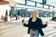 © Strelciuc - Happy caucasian woman with blue hair cheering outside while holding a mobile