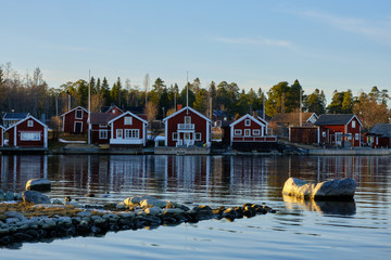 Wall Mural - Small red houses by the sea with stones in the foreground