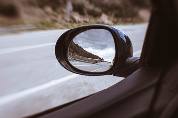 Oval mirror car reflecting an empty road with storm rainy clouds