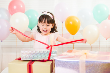 Wall Mural - toddler girl unpacking birthday gift box on her birthday party