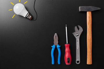 Workshop tools that can be found at most homes composition copyspace for text on a black background. conceptual photo with a play of light and shadow top view. idea lamp