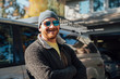© Inti St. Clair - Smiling bearded man in sunglasses and hat standing next to truck in driveway