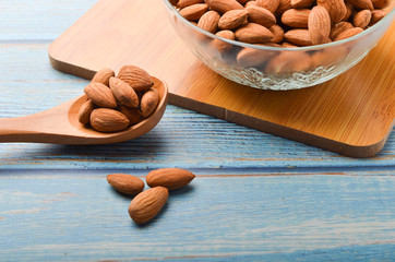 Close up view of healthy almond milk in drinking glass with seed in bowl on wooden background.