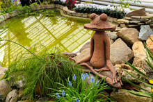 Frog Statue Near Ornamental Pond Among Green Plants In Garden, Soft Focus