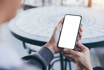 Mockup image blank white screen cell phone.woman hand holding texting using mobile on desk at coffee shop.background empty space for advertise text.people contact marketing business,technology