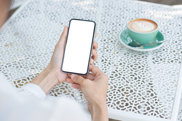 Mockup image blank white screen cell phone.woman hand holding texting using mobile on desk at coffee shop.background empty space for advertise text.people contact marketing business,technology