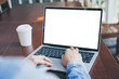 © panitan - mockup image blank screen computer with white background for advertising text,hand woman using laptop contact business search information on desk at coffee shop.marketing and creative design