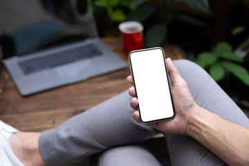 Mockup image blank white screen cell phone.man hand holding texting using mobile on desk at coffee shop.background empty space for advertise text.people contact marketing business,technology