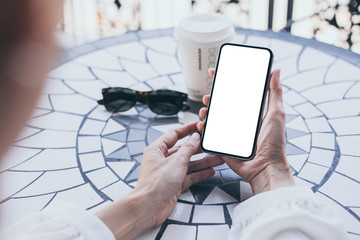 Mockup image blank white screen cell phone.woman hand holding texting using mobile on desk at coffee shop.background empty space for advertise text.people contact marketing business,technology