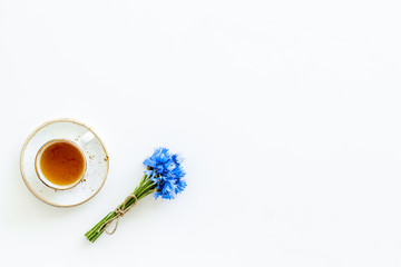 Poster - Summer tea party. Cup near cornflowers bouquet on white background top-down copy space