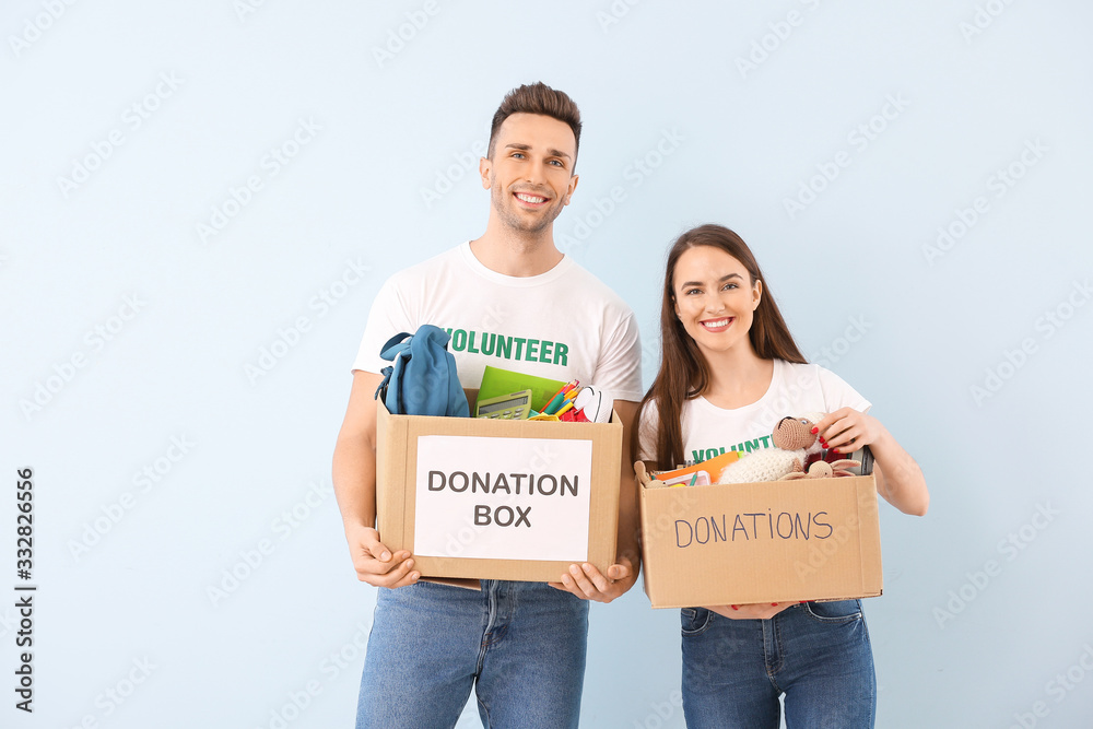 Volunteers with donations for orphans on color background